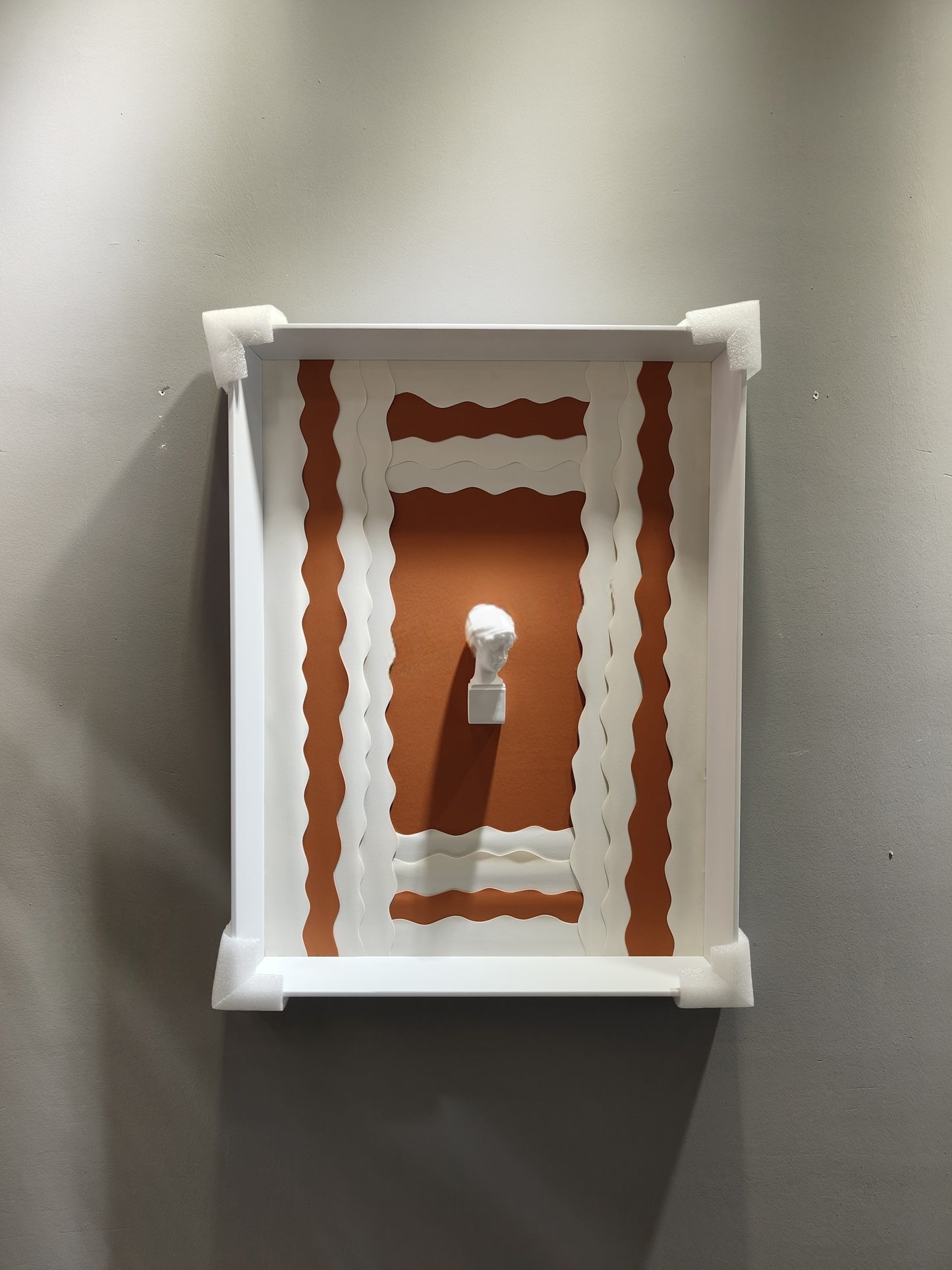 3D sculptural bust wall art with terracotta wave background and white frame – 50×70cm